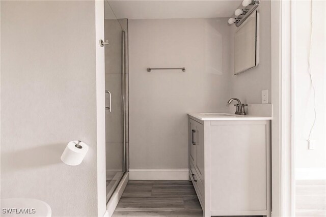 bathroom featuring a shower with shower door, hardwood / wood-style flooring, and vanity