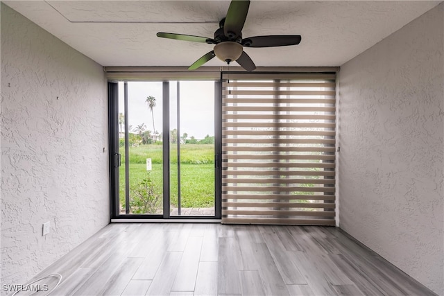 unfurnished room featuring a textured ceiling, light hardwood / wood-style flooring, ceiling fan, and expansive windows