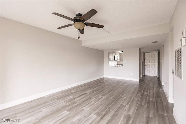 empty room featuring a textured ceiling, hardwood / wood-style floors, and ceiling fan