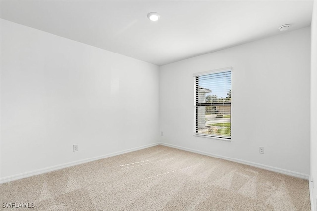 unfurnished room featuring baseboards and light colored carpet