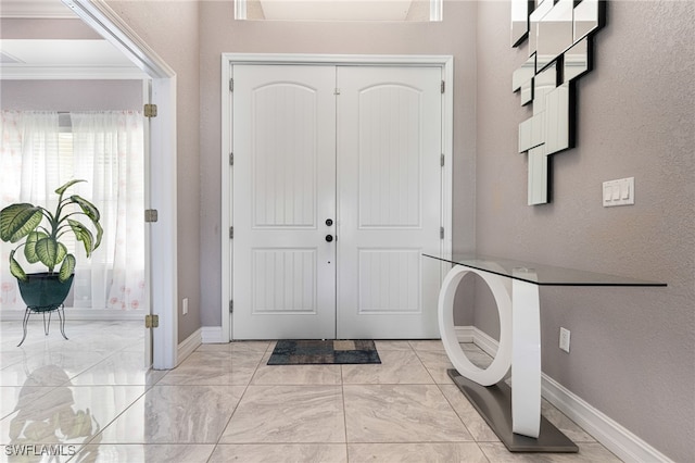 entrance foyer featuring crown molding and light tile patterned floors