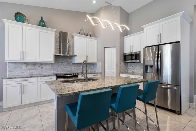 kitchen with wall chimney range hood, decorative backsplash, sink, and stainless steel appliances