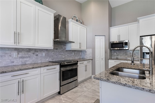 kitchen with backsplash, wall chimney exhaust hood, white cabinetry, appliances with stainless steel finishes, and sink