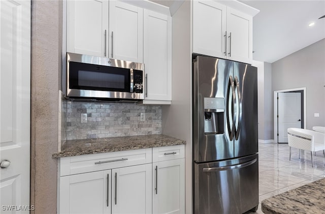 kitchen with light tile patterned flooring, appliances with stainless steel finishes, stone countertops, tasteful backsplash, and white cabinetry