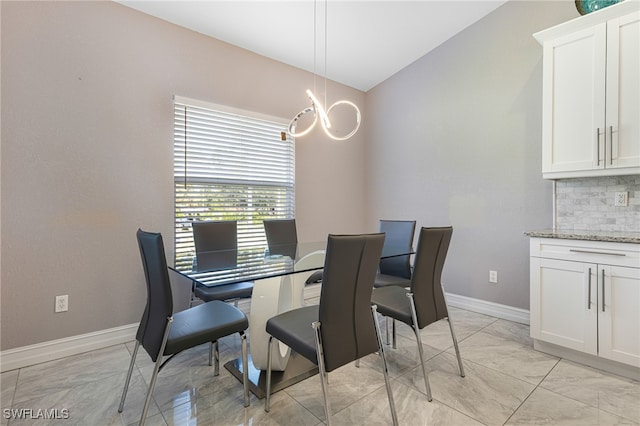 tiled dining room featuring an inviting chandelier and lofted ceiling