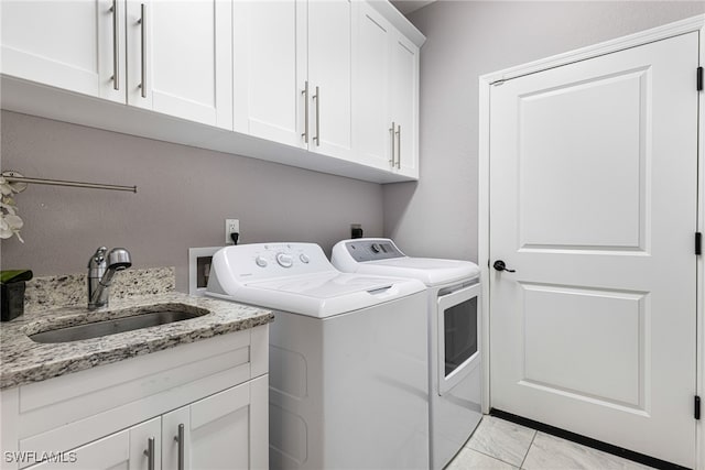 washroom featuring sink, washing machine and clothes dryer, light tile patterned floors, and cabinets