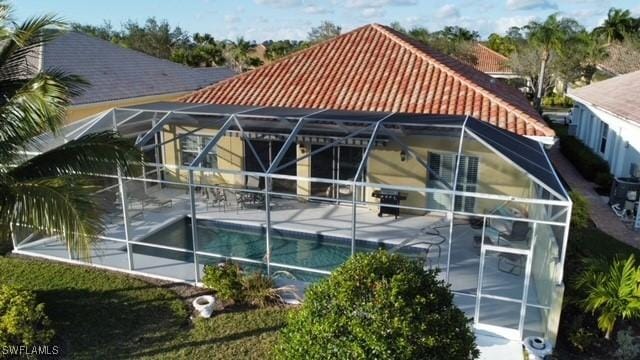 exterior space with a tile roof, an outdoor pool, glass enclosure, and a patio