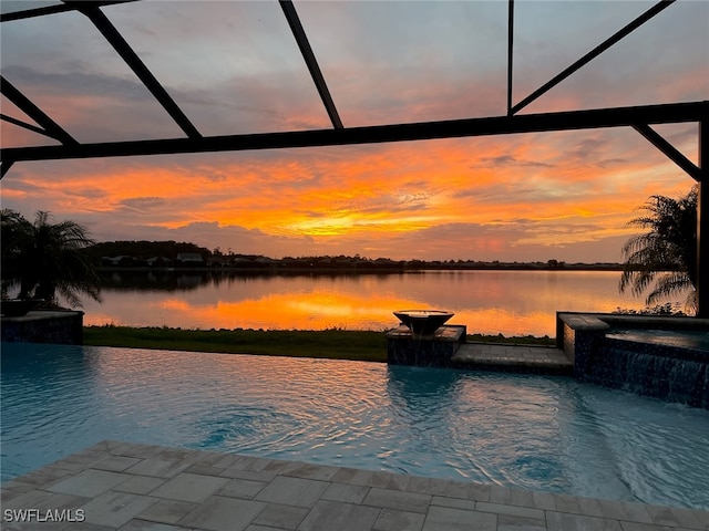 pool at dusk featuring pool water feature and a water view