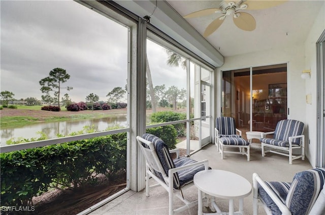 sunroom with ceiling fan and a water view