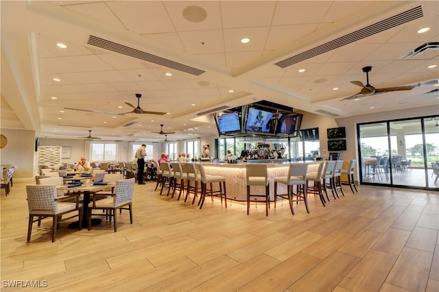 dining room with light hardwood / wood-style floors, ceiling fan, and bar area