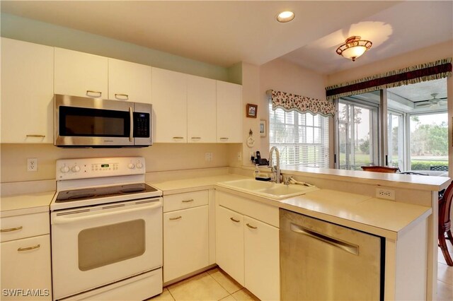 kitchen featuring appliances with stainless steel finishes, light tile patterned flooring, white cabinetry, kitchen peninsula, and sink