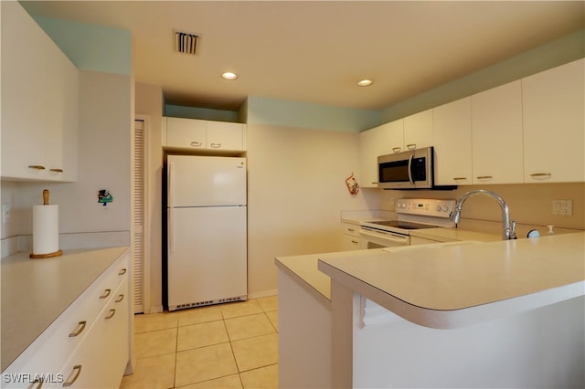 kitchen with light tile patterned flooring, sink, white cabinetry, kitchen peninsula, and white appliances