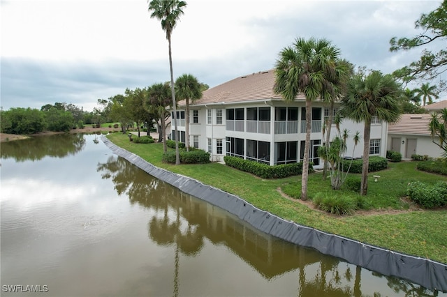 rear view of house with a water view, a sunroom, and a yard