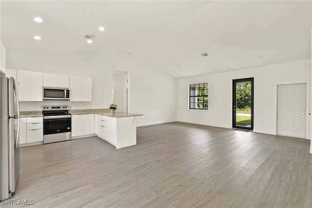 kitchen with stainless steel appliances, vaulted ceiling, white cabinets, and light hardwood / wood-style flooring