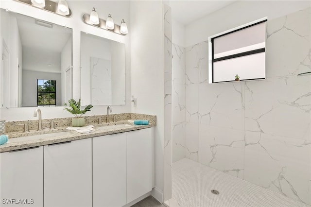 bathroom with visible vents, a sink, a marble finish shower, and double vanity