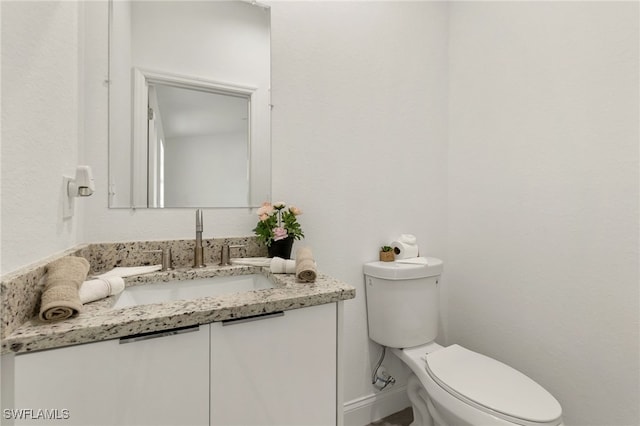 half bathroom featuring baseboards, vanity, and toilet