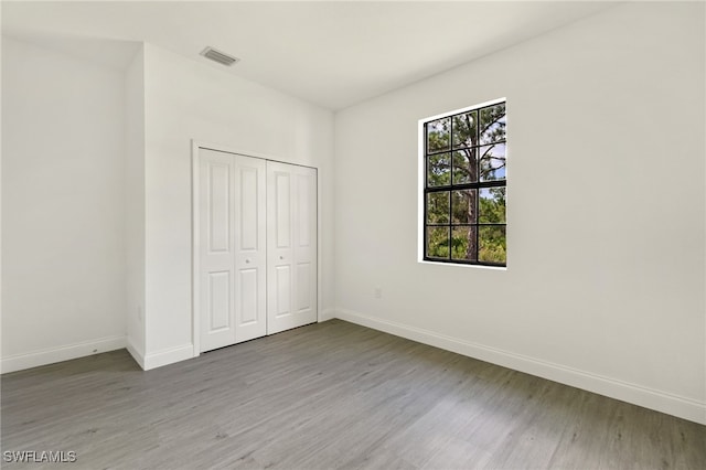 unfurnished bedroom featuring a closet, hardwood / wood-style floors, and multiple windows