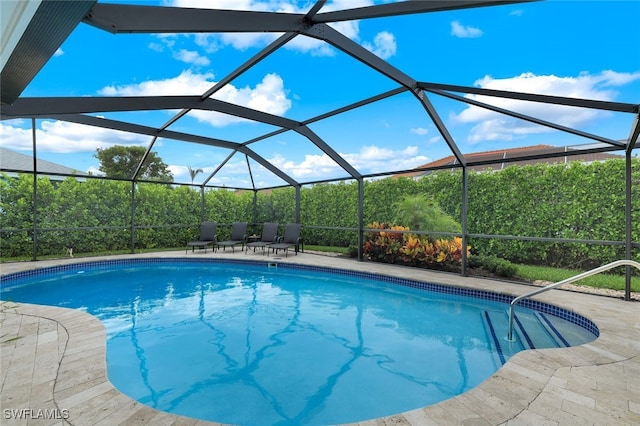 view of pool with glass enclosure and a patio area