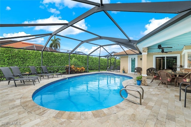 view of pool with glass enclosure, outdoor lounge area, ceiling fan, and a patio