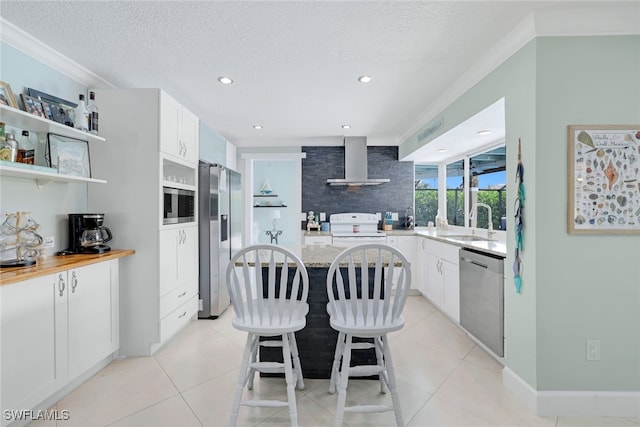 kitchen featuring white cabinets, stainless steel appliances, wall chimney exhaust hood, a breakfast bar area, and a textured ceiling