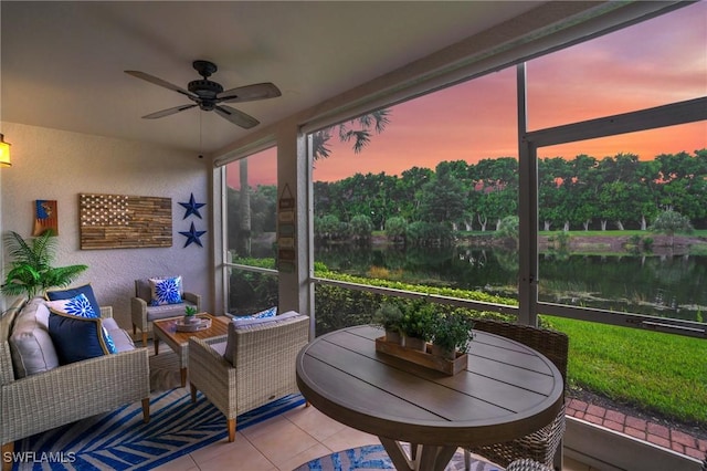 sunroom with ceiling fan and a water view