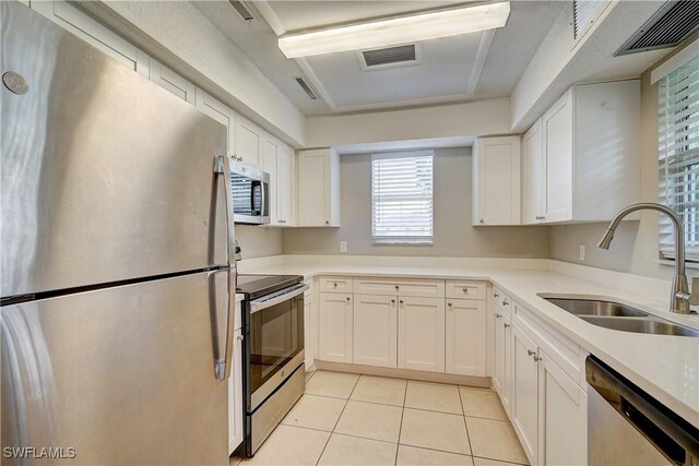 kitchen featuring stainless steel appliances, white cabinets, light tile patterned floors, and sink