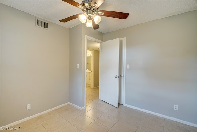 tiled spare room featuring a textured ceiling and ceiling fan