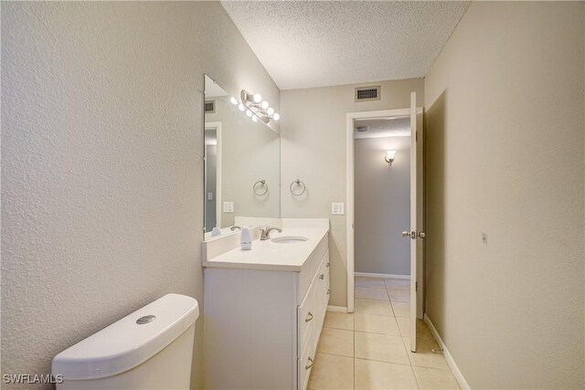 bathroom featuring vanity, toilet, a textured ceiling, and tile patterned floors