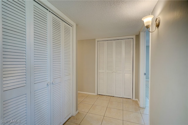 corridor with a textured ceiling and light tile patterned floors