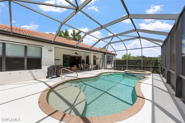 view of pool with glass enclosure, an in ground hot tub, ceiling fan, and a patio area