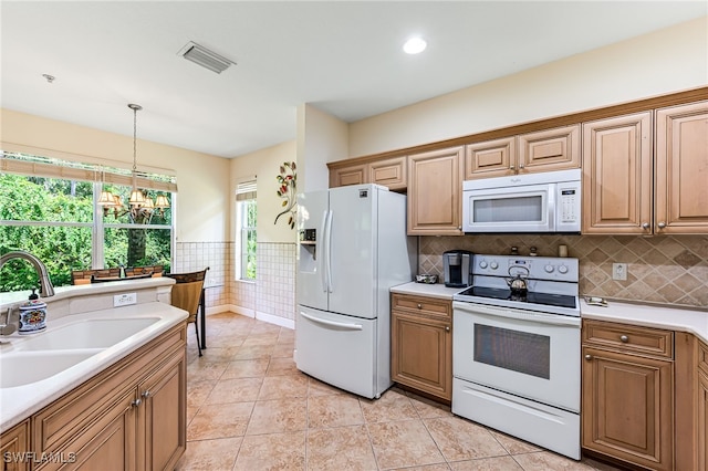 kitchen with white appliances, pendant lighting, light tile patterned floors, sink, and a chandelier