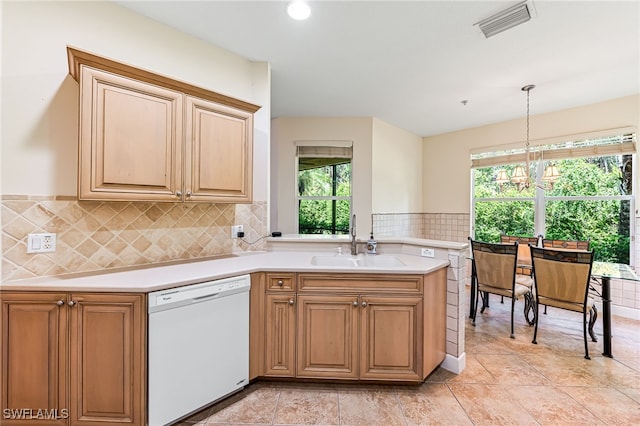 kitchen featuring white dishwasher, pendant lighting, a notable chandelier, kitchen peninsula, and sink