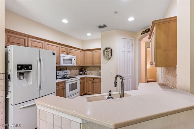 kitchen with white appliances, backsplash, kitchen peninsula, and sink