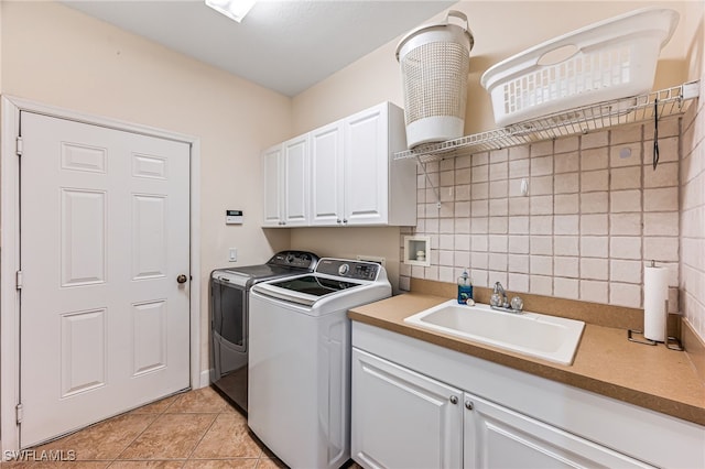 clothes washing area featuring cabinets, light tile patterned floors, washer and dryer, tile walls, and sink