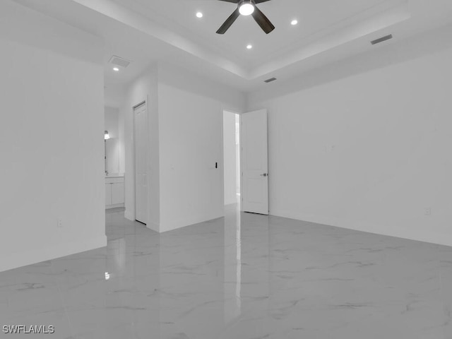 spare room with a tray ceiling and ceiling fan