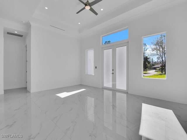 unfurnished living room with a tray ceiling, ceiling fan, french doors, and crown molding