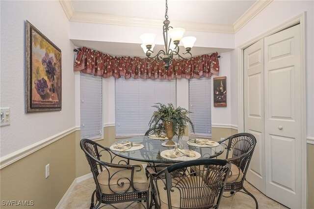 dining area with ornamental molding, a notable chandelier, and light tile patterned flooring