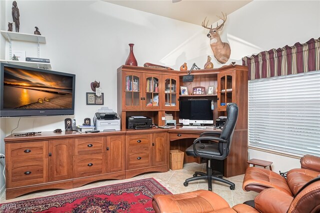 home office featuring vaulted ceiling, built in desk, and light tile patterned floors