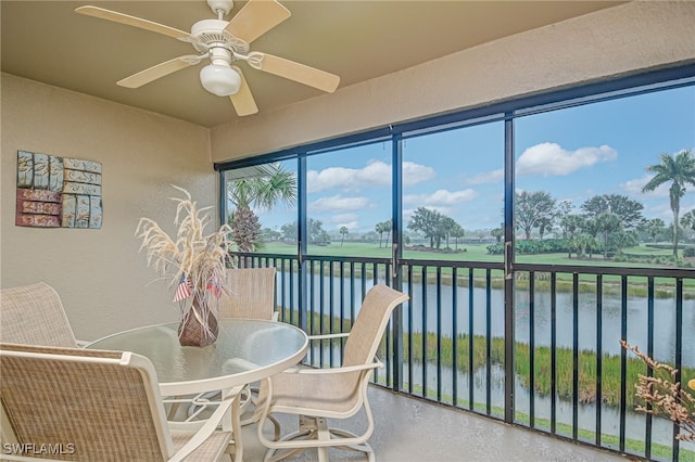 sunroom / solarium with a water view and ceiling fan