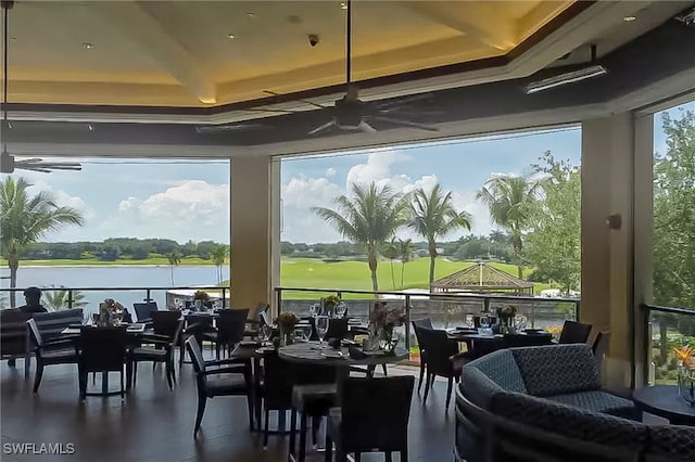 interior space with a tray ceiling, a water view, and ceiling fan