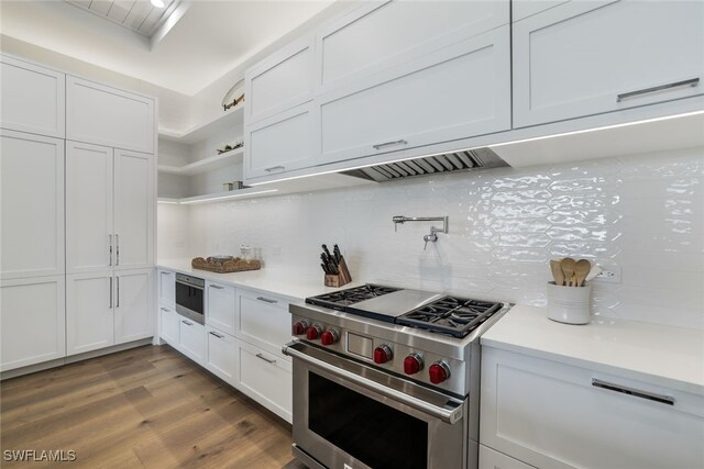 kitchen with hardwood / wood-style floors, backsplash, white cabinetry, and stainless steel appliances