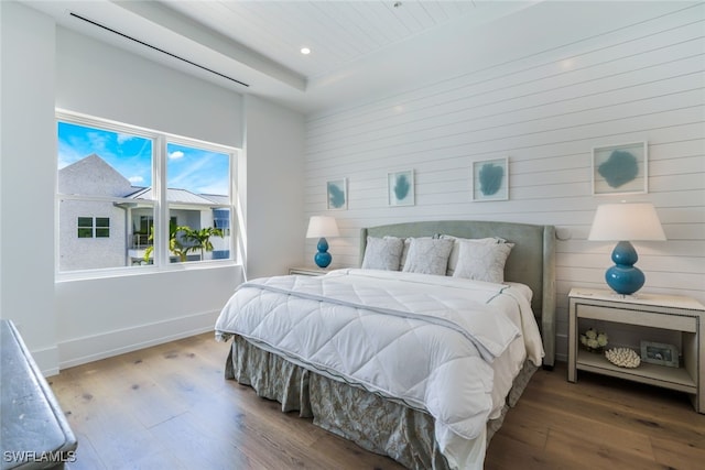 bedroom with wood walls, recessed lighting, wood finished floors, and baseboards