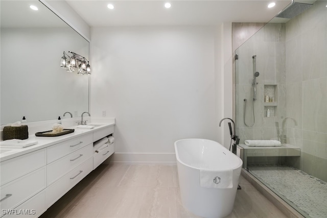 full bath featuring double vanity, a freestanding bath, a sink, and tiled shower