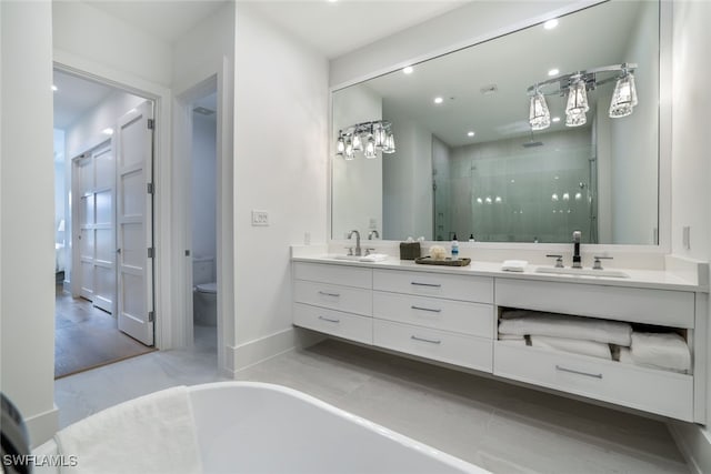 full bath with toilet, a sink, baseboards, a shower stall, and double vanity