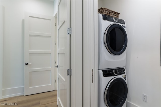 washroom featuring stacked washer / drying machine and light hardwood / wood-style flooring