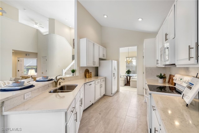 kitchen featuring high vaulted ceiling, light stone countertops, white appliances, and white cabinetry