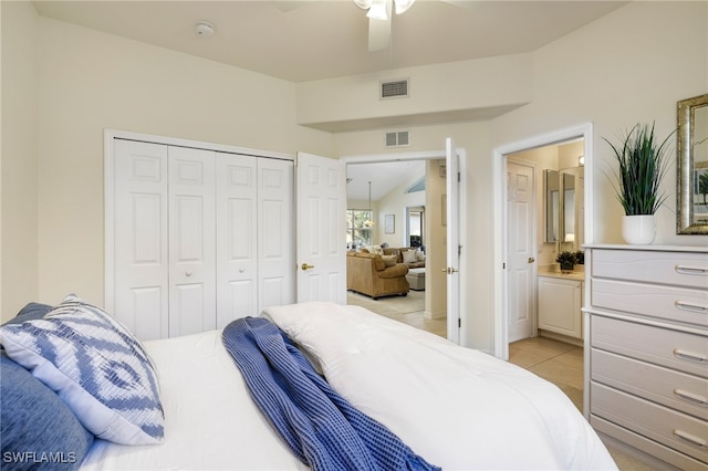 bedroom with ceiling fan, ensuite bath, a closet, light tile patterned flooring, and lofted ceiling