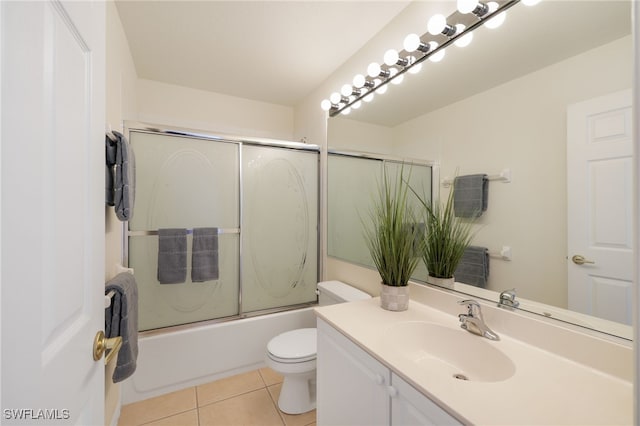 full bathroom featuring toilet, bath / shower combo with glass door, tile patterned flooring, and vanity