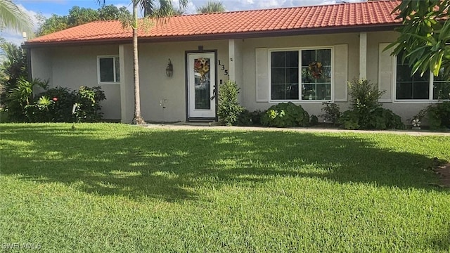 view of front of home with a front lawn, a tile roof, and stucco siding