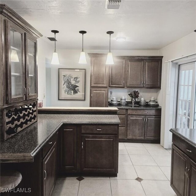 kitchen featuring hanging light fixtures, light tile patterned flooring, and dark brown cabinetry